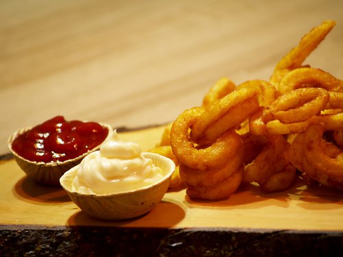 Gekringelte Pommes mit zwei Schälchen Ketchup und Mayonaise